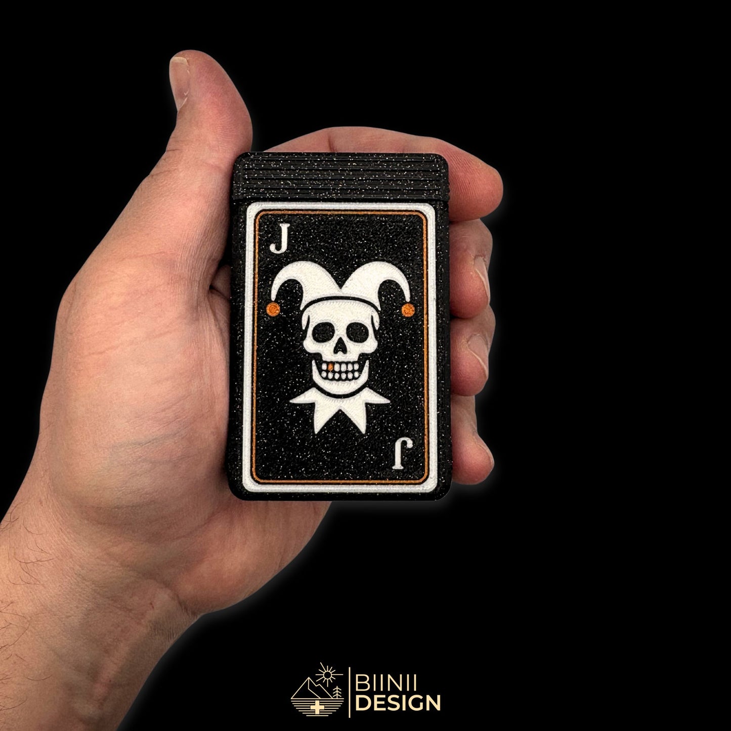 Compact Joker skull pill box in hand, galaxy black PLA with copper tooth, playing card style, perfect for travel or daily medication organization. Keywords: small pill organizer, gothic pill case, portable pill box, travel medication holder