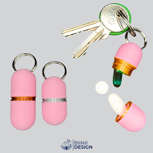 Elegant pink keychain pill holder with gold ring on keys, opened to show compact capacity for daily medication. Premium travel pill case.