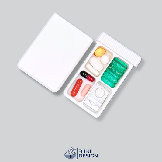 Double-row 4-compartment pill organizer open, filled with supplements and blister-cut meds, Swiss-made design by Biinii Design.