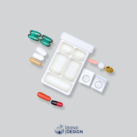The 5-compartment pill case with its 4+1 hybrid layout displayed with pills to showcase its large capacity for blister packs. A Swiss-crafted Biinii Design piece.