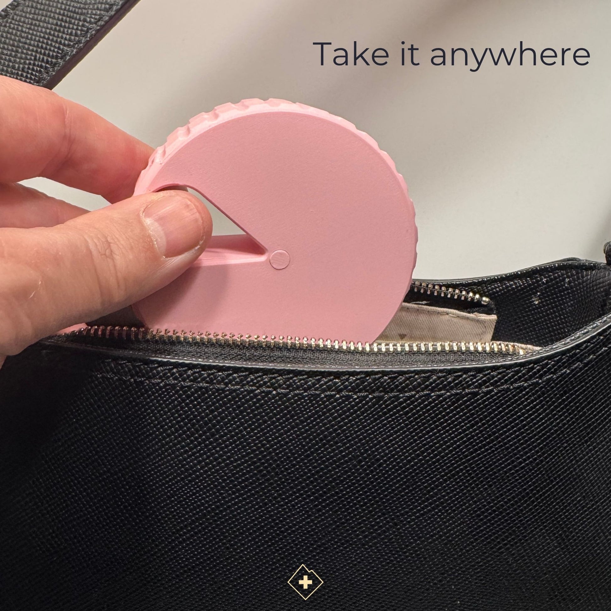 Round monochrome pink magnetic pill organizer safely tucked inside a handbag, highlighting its compact travel size.