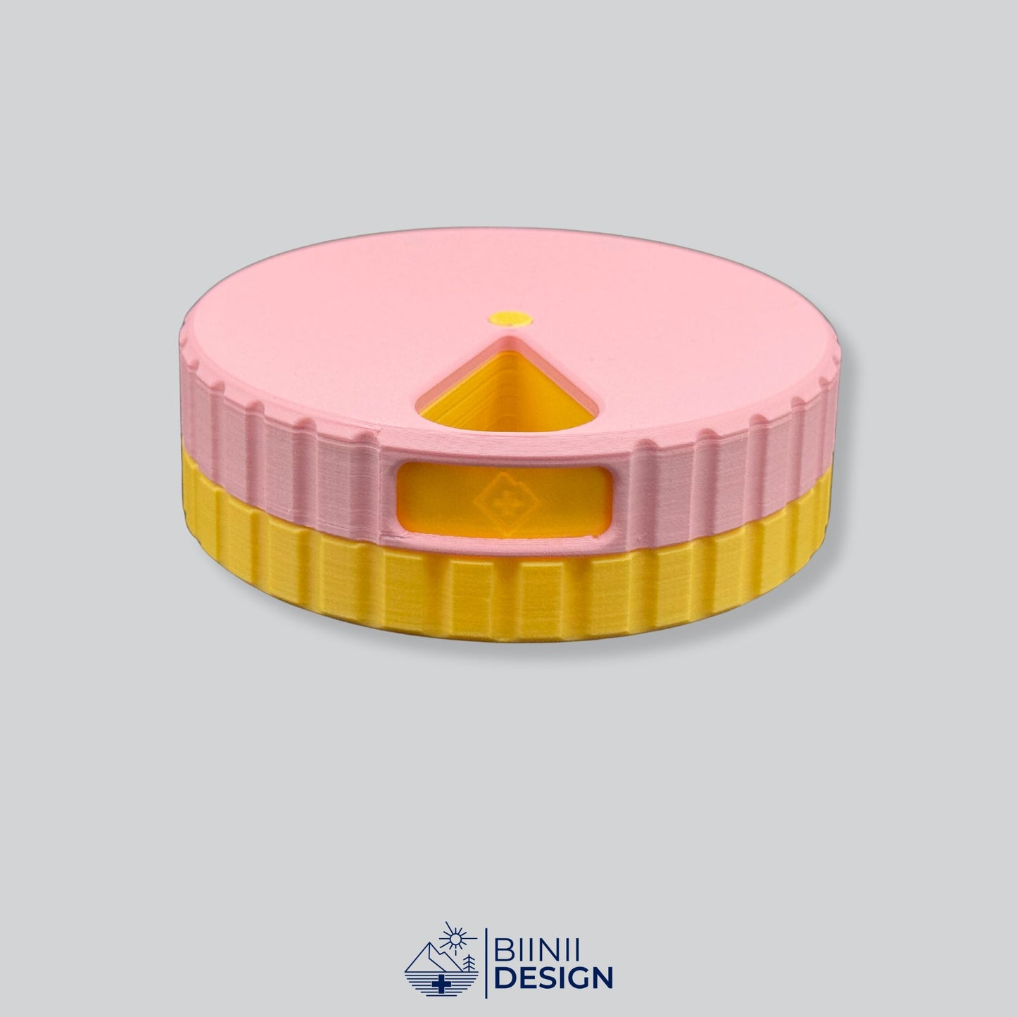 Pink lid contrasting with the yellow base on the round magnetic pill case.