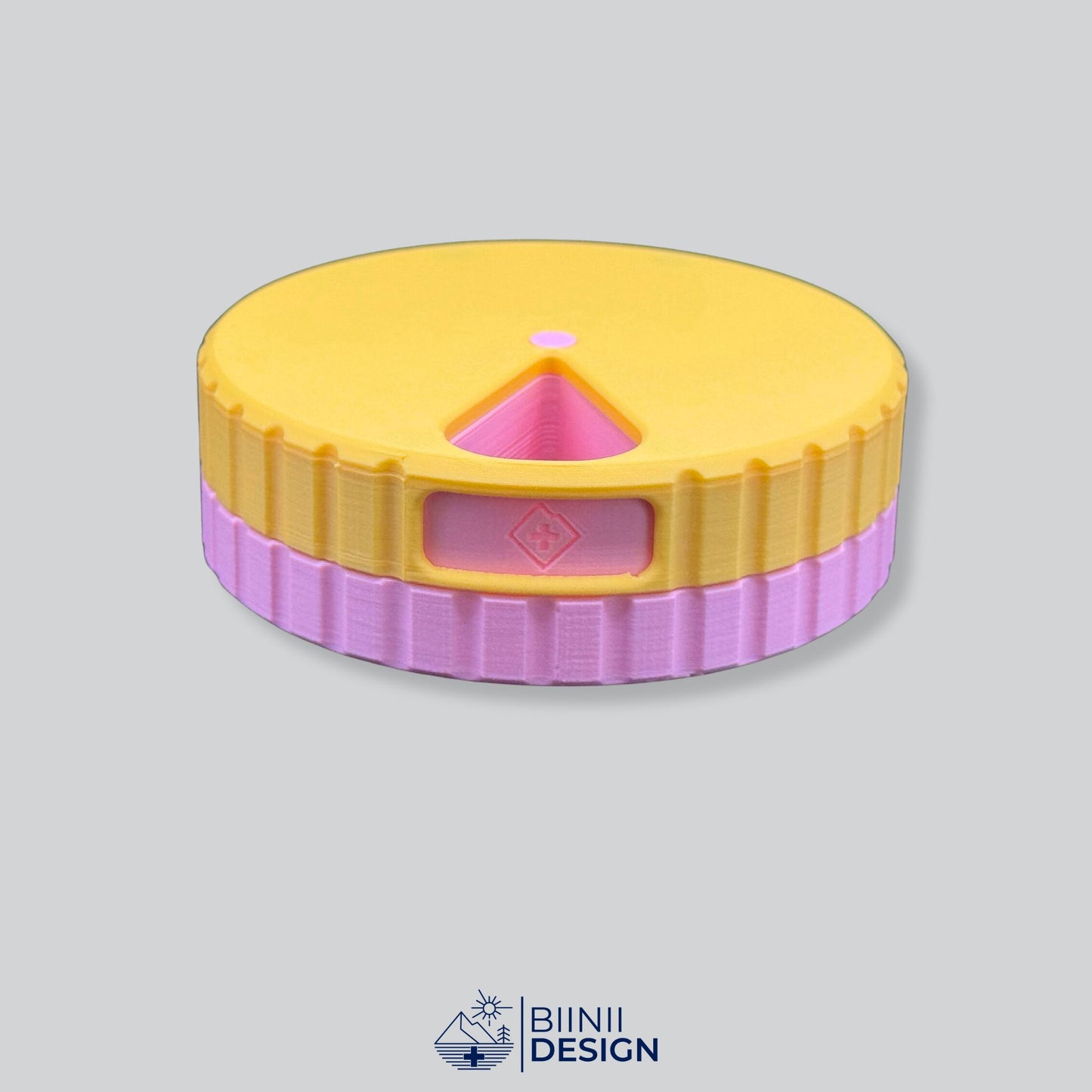 Yellow lid contrasting with the pink base on the round magnetic pill case.
