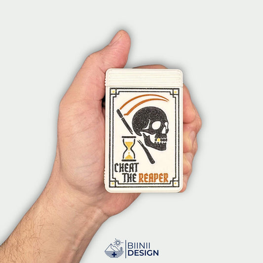 Cheat the Reaper White Edition pill organizer held in hand for scale. Matte white gothic pill box with slide closure.