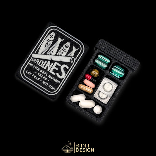 Sardines artistic pill organizer cover beside 5-compartment tray. Secure slide closure filled with vegan supplements and non-fish capsules.