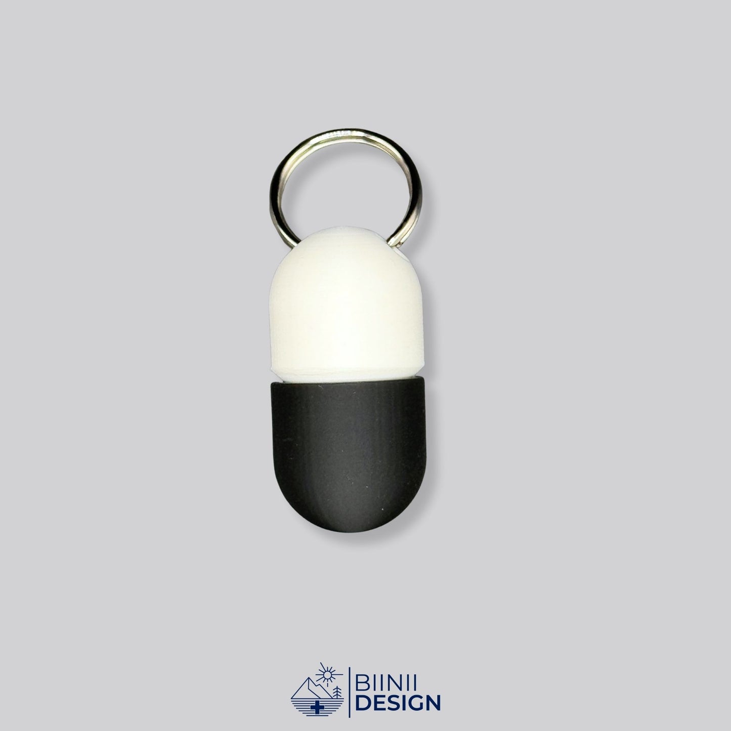 Closed white and black keyring pillbox with sleek capsule-shaped design — compact, Swiss-made, and customizable travel pill case.
Keywords: black and white pillbox, capsule pill case, keyring pill holder, compact travel pillbox, Swiss-made pill organizer