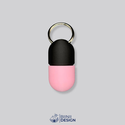 Zweifarbige Compact-Pillendose für den Schlüsselanhänger, Oberteil in Schwarz und Unterteil in Rosa.