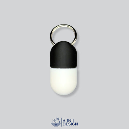 Zweifarbige Compact-Pillendose für den Schlüsselanhänger, Oberteil in Schwarz und Unterteil in Weiß.