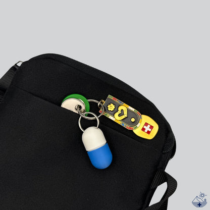 Weiß-blaue Compact-Pillendose für den Schlüsselanhänger am Schlüsselring mit Schlüsseln, verstaut in einer kleinen Alltagstasche.