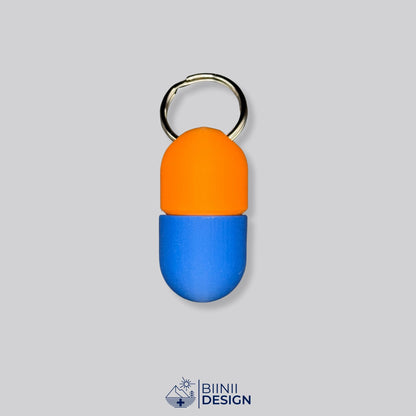 Zweifarbige Compact-Pillendose für den Schlüsselanhänger, Oberteil in Orange und Unterteil in Blau.