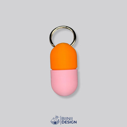 Zweifarbige Compact-Pillendose für den Schlüsselanhänger, Oberteil in Orange und Unterteil in Rosa.