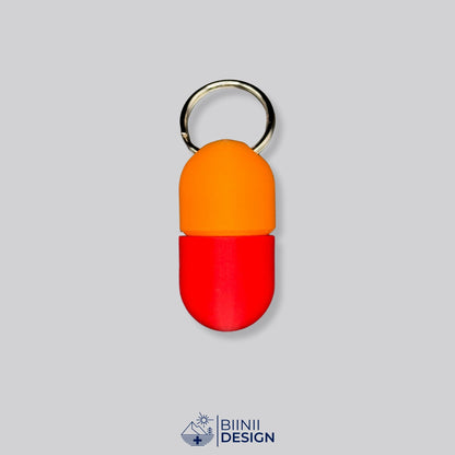 Zweifarbige Compact-Pillendose für den Schlüsselanhänger, Oberteil in Orange und Unterteil in Rot.