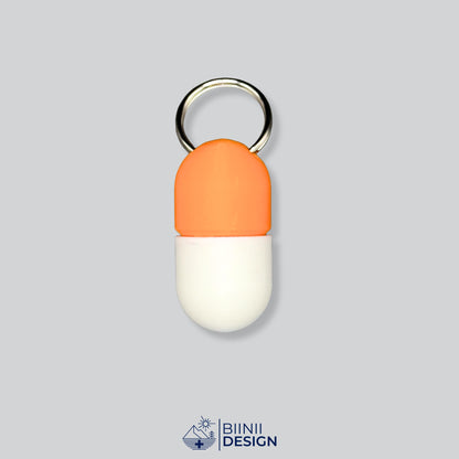 Zweifarbige Compact-Pillendose für den Schlüsselanhänger, Oberteil in Orange und Unterteil in Weiß.