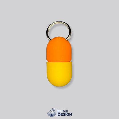 Zweifarbige Compact-Pillendose für den Schlüsselanhänger, Oberteil in Orange und Unterteil in Gelb.