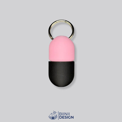 Zweifarbige Compact-Pillendose für den Schlüsselanhänger, Oberteil in Rosa und Unterteil in Schwarz.