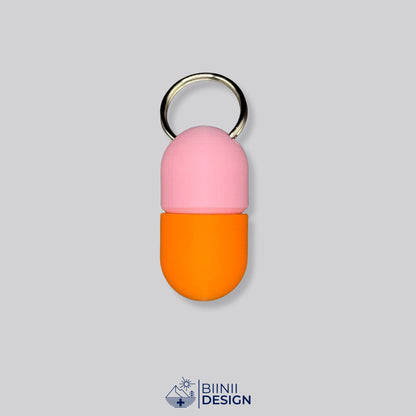 Zweifarbige Compact-Pillendose für den Schlüsselanhänger, Oberteil in Rosa und Unterteil in Orange.