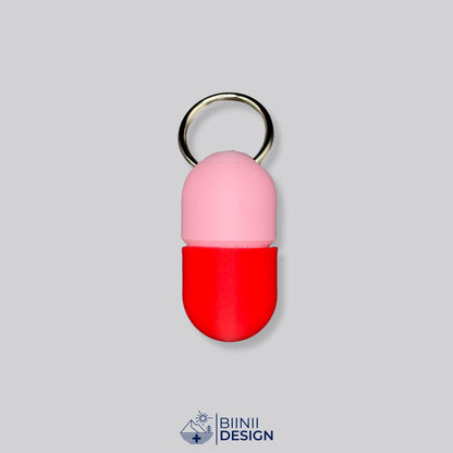 Zweifarbige Compact-Pillendose für den Schlüsselanhänger, Oberteil in Rosa und Unterteil in Rot.