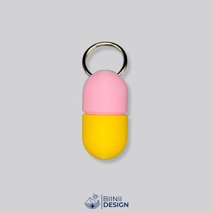 Zweifarbige Compact-Pillendose für den Schlüsselanhänger, Oberteil in Rosa und Unterteil in Gelb.
