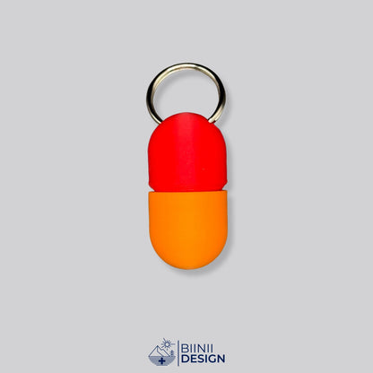Zweifarbige Compact-Pillendose für den Schlüsselanhänger, Oberteil in Rot und Unterteil in Orange.