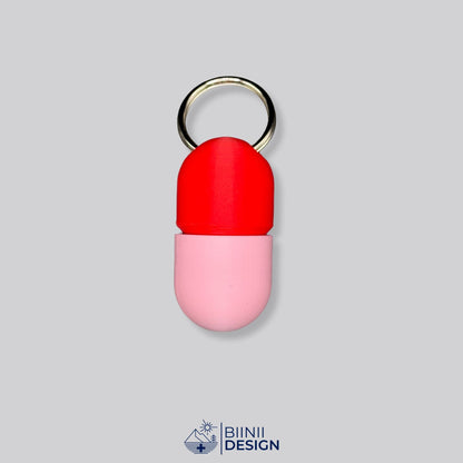 Zweifarbige Compact-Pillendose für den Schlüsselanhänger, Oberteil in Rot und Unterteil in Rosa.
