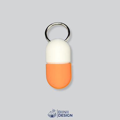 Zweifarbige Compact-Pillendose für den Schlüsselanhänger, Oberteil in Weiß und Unterteil in Orange.