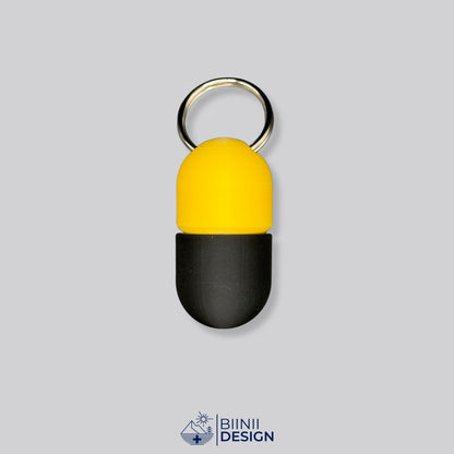 Zweifarbige Compact-Pillendose für den Schlüsselanhänger, Oberteil in Gelb und Unterteil in Schwarz.