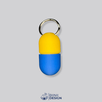 Zweifarbige Compact-Pillendose für den Schlüsselanhänger, Oberteil in Gelb und Unterteil in Blau.