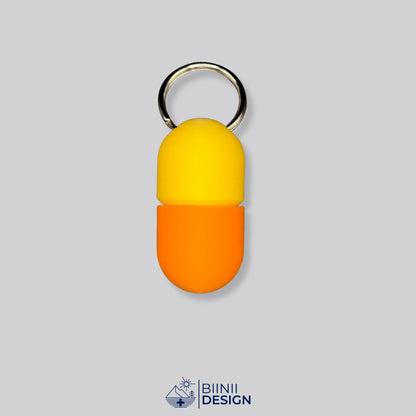 Zweifarbige Compact-Pillendose für den Schlüsselanhänger, Oberteil in Gelb und Unterteil in Orange.