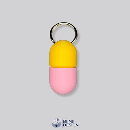 Zweifarbige Compact-Pillendose für den Schlüsselanhänger, Oberteil in Gelb und Unterteil in Rosa.