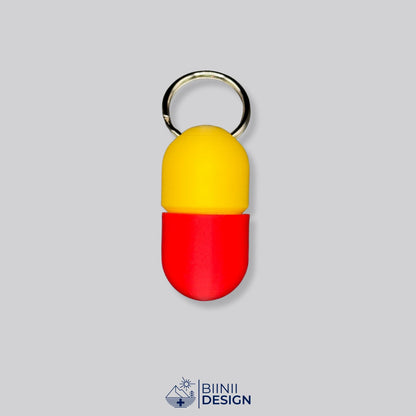 Zweifarbige Compact-Pillendose für den Schlüsselanhänger, Oberteil in Gelb und Unterteil in Rot.