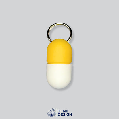 Zweifarbige Compact-Pillendose für den Schlüsselanhänger, Oberteil in Gelb und Unterteil in Weiß.