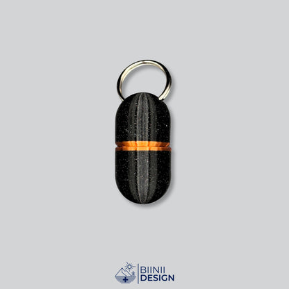 Pilulier porte-clés Deluxe Compact en galaxy black avec un accent cuivré à la jonction.