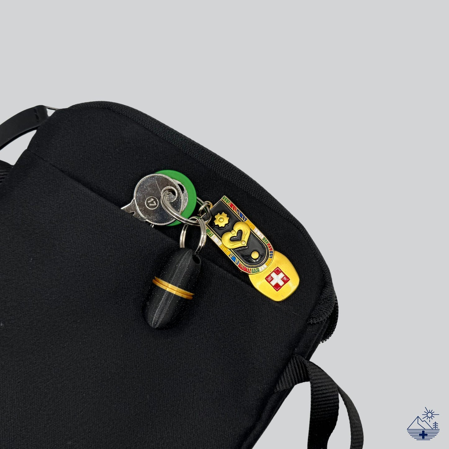 Premium black keychain pill holder with gold accent on Swiss flag keyring, placed into travel pouch. Compact pill case for short trips.