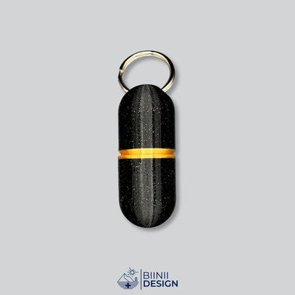 Pilulier porte-clés Deluxe Large en galaxy black avec un accent doré à la jonction.