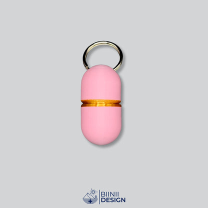 Compact-Deluxe-Pillendose für den Schlüsselanhänger in zartem Rosa mit Gold-Akzent am Übergang.