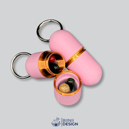 Large-Deluxe-Pillendose in zartem Rosa mit Kupfer-Akzent, Unterteil abgeschraubt mit 4 Kapseln und Tabletten, daneben ein geschlossenes Gold-Modell.