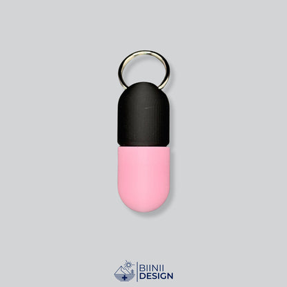 Zweifarbige Large-Pillendose für den Schlüsselanhänger, Oberteil in Schwarz und Unterteil in Rosa.