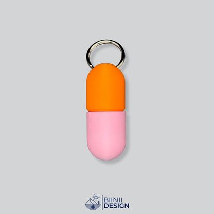 Zweifarbige Large-Pillendose für den Schlüsselanhänger, Oberteil in Orange und Unterteil in Rosa.