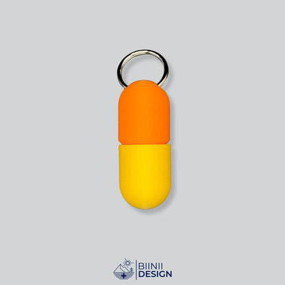 Zweifarbige Large-Pillendose für den Schlüsselanhänger, Oberteil in Orange und Unterteil in Gelb.