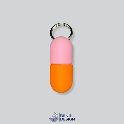 Zweifarbige Large-Pillendose für den Schlüsselanhänger, Oberteil in Rosa und Unterteil in Orange.