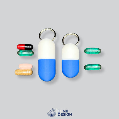 Weiß-blaue Large-Pillendose für den Schlüsselanhänger links mit vier verschiedenen Tabletten, rechts das Compact-Modell mit zwei.