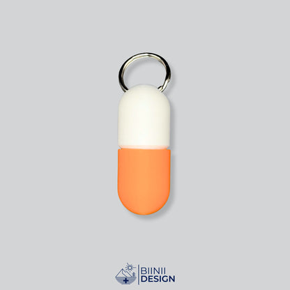 Zweifarbige Large-Pillendose für den Schlüsselanhänger, Oberteil in Weiß und Unterteil in Orange.