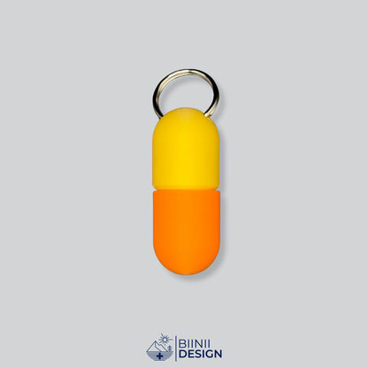 Zweifarbige Large-Pillendose für den Schlüsselanhänger, Oberteil in Gelb und Unterteil in Orange.