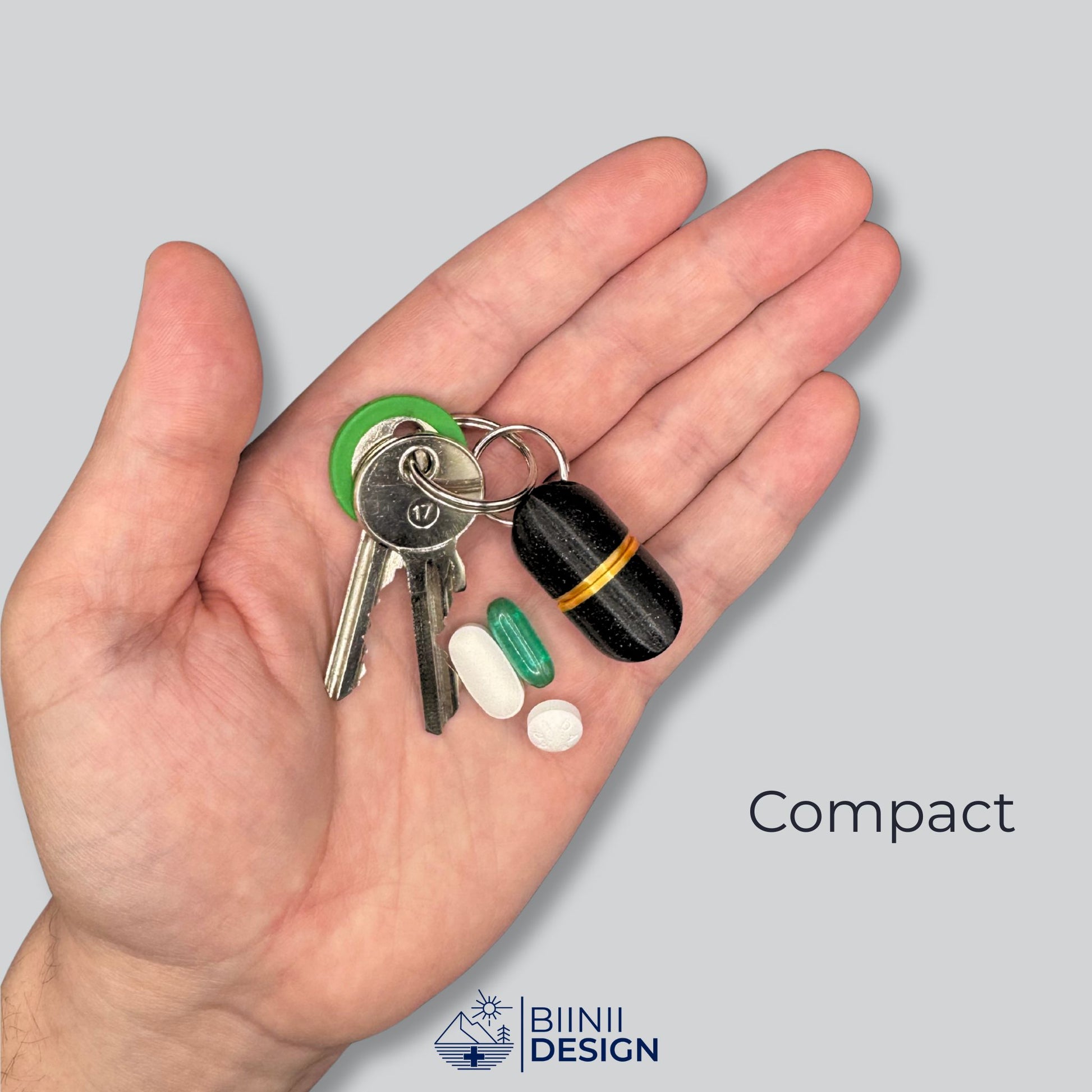 Compact deluxe pillbox in galaxy black and gold shown on a palm next to keys and supplements. Small, discreet, and travel-ready.
Keywords: compact pill holder, keychain medication case, vitamin container, travel pill organizer, Biinii Design