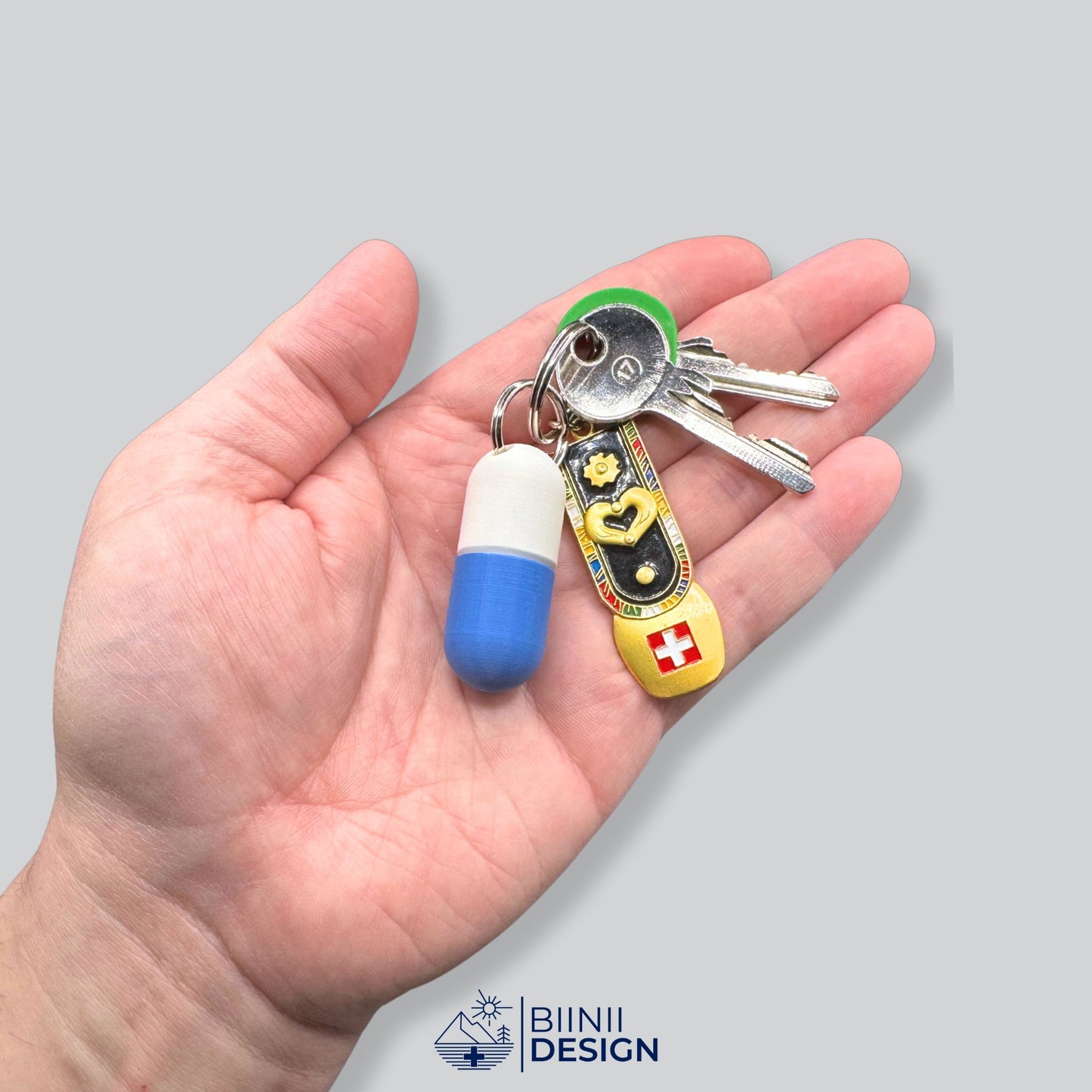 Large white and blue keyring pillbox shown on a hand with Swiss keyring. Spacious capsule design for vitamins, meds, or supplements on the go.
Keywords: large keyring pillbox, travel capsule pill case, Swiss-made pill organizer, supplement holder