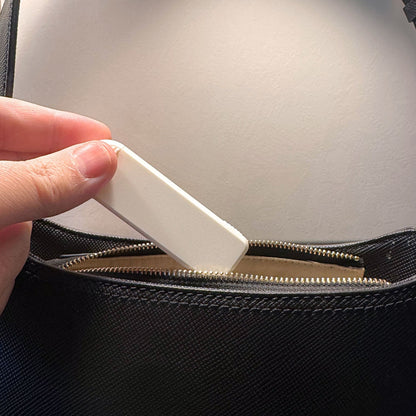 Pilulier compact 4 compartiments blanc fermé, glissé dans un sac à main en cuir bleu.