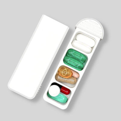 Swiss-made four-compartment pill organizer shown open with varied pills and supplements, its sliding lid placed beside the tray to clearly reveal the internal layout.