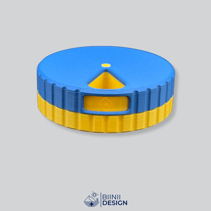 Round magnetic 7-day pill organizer with a blue lid and a yellow base, days in French and German.