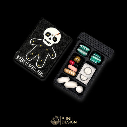 Healing Voodoo art edition pill organizer: silver voodoo doll with copper stitches on galaxy black, beside a filled 5-compartment base.