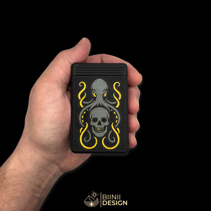 Closed Kraken's Whisper art edition pill organizer held in hand for scale, anthracite kraken and skull, gold suckers, gold eyes and the gold tooth.